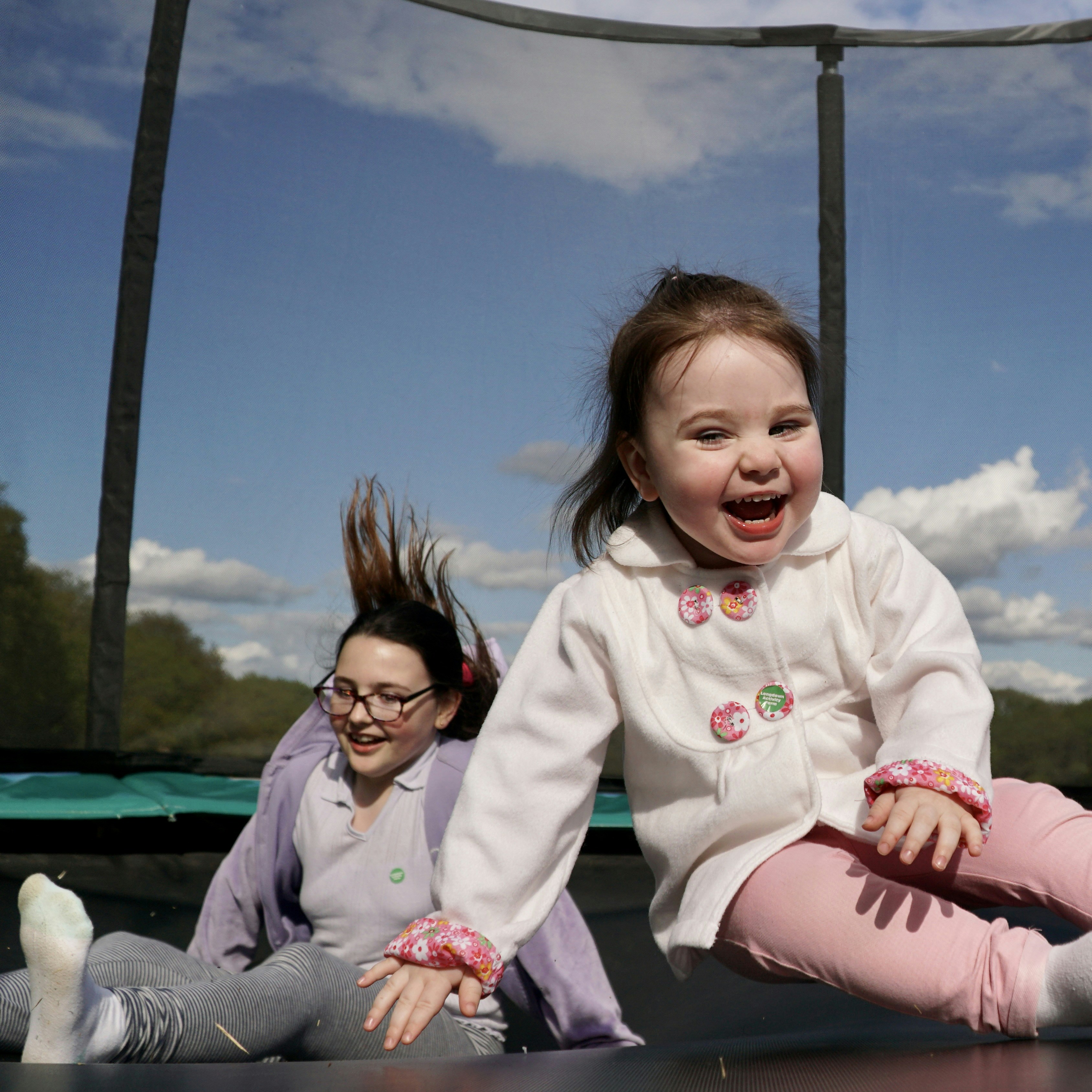 A young girl sitting on top of a trampoline