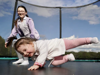 A little girl is playing on a trampoline