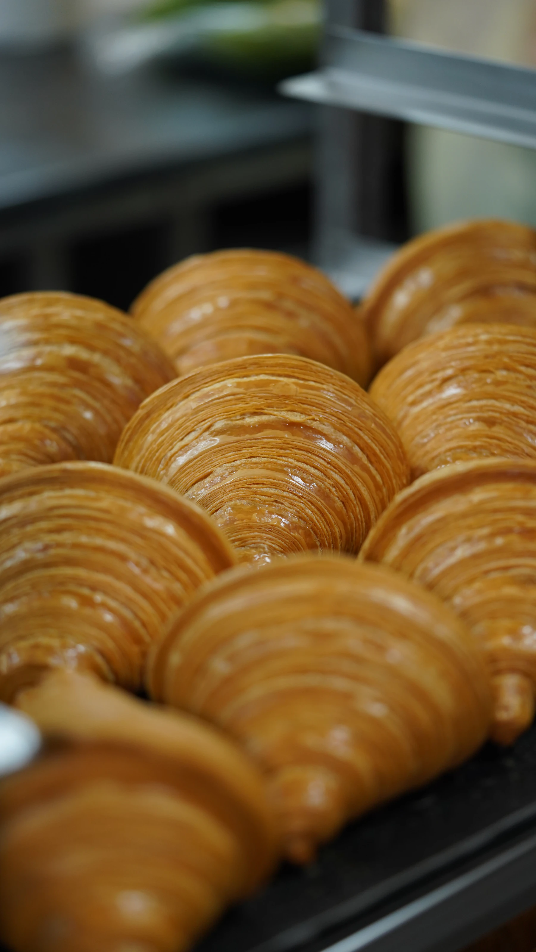 A close-up of baked croissants with their thin laminated layers showing