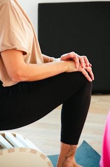 A woman sitting on a yoga mat with her hands on her knees