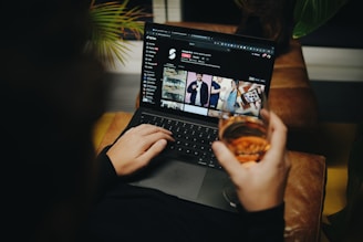A person sitting on a couch with a laptop