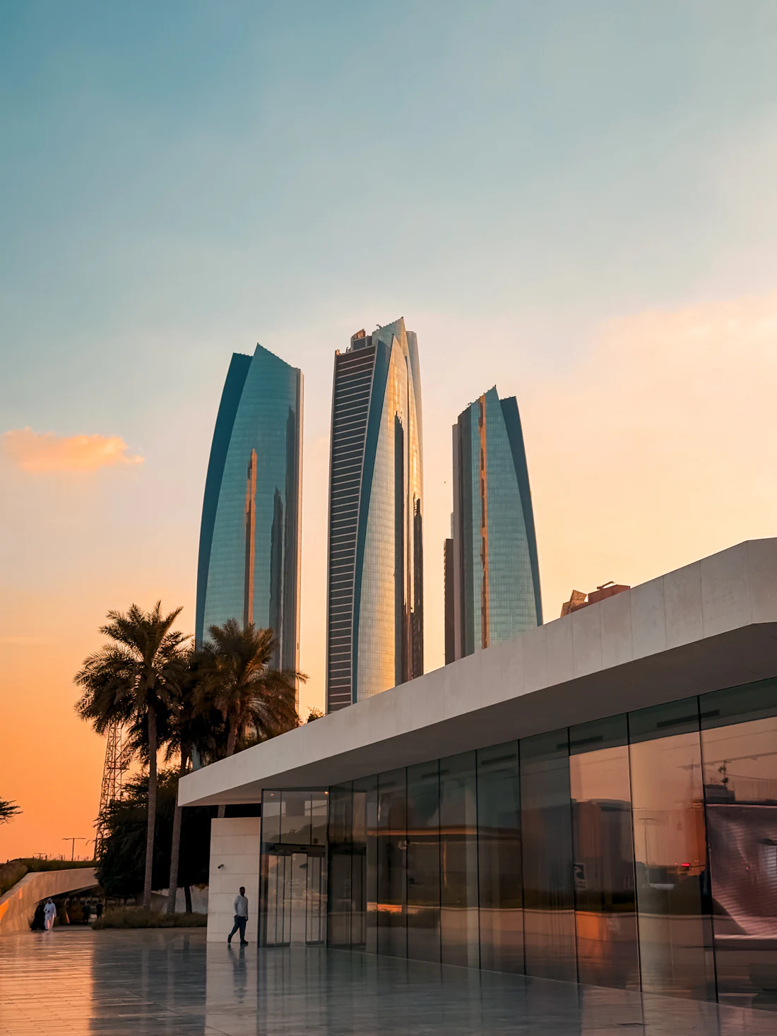 Glass towers in Abu Dhabi reflecting an orange evening sky