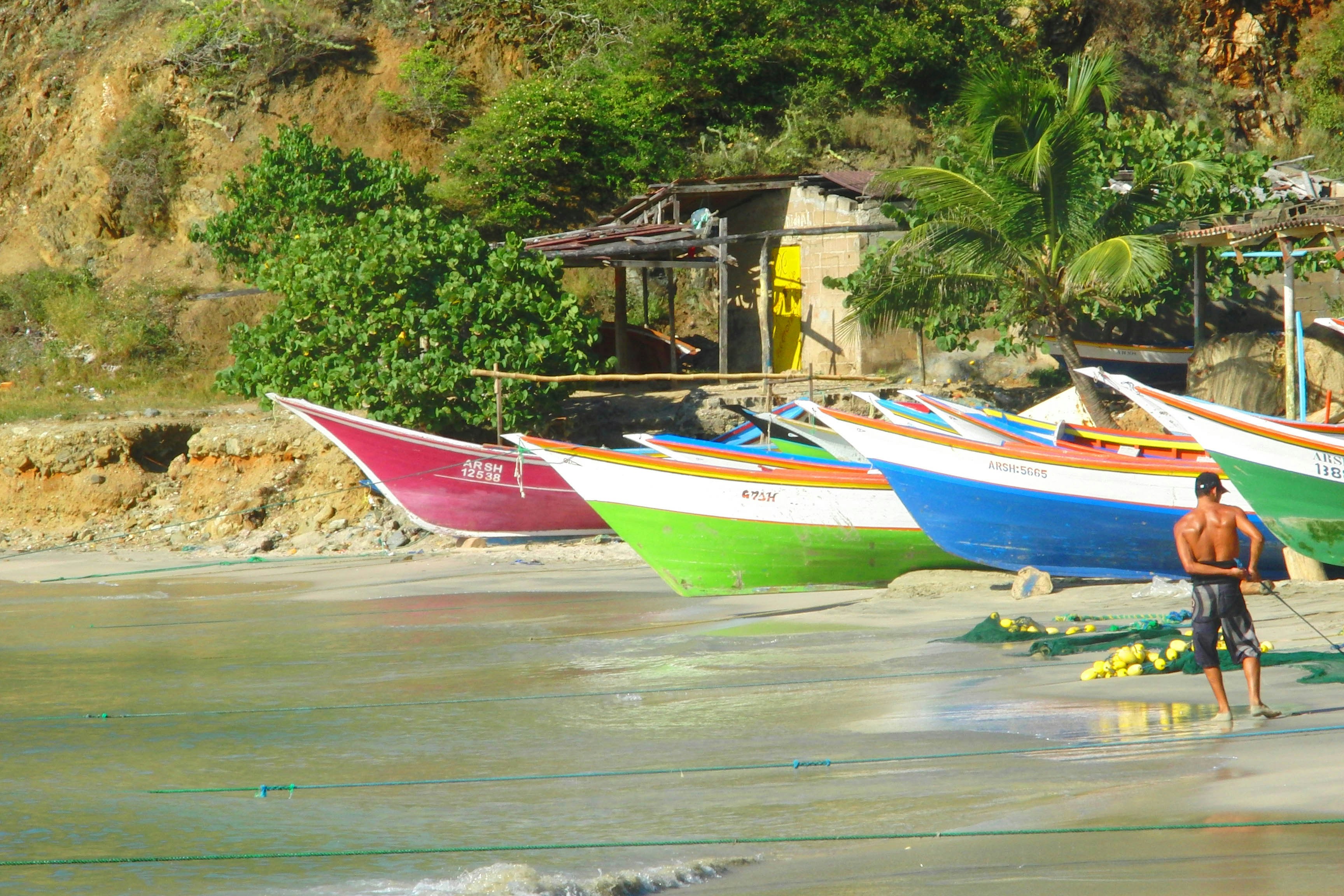 A man standing on a beach next to a row of boats