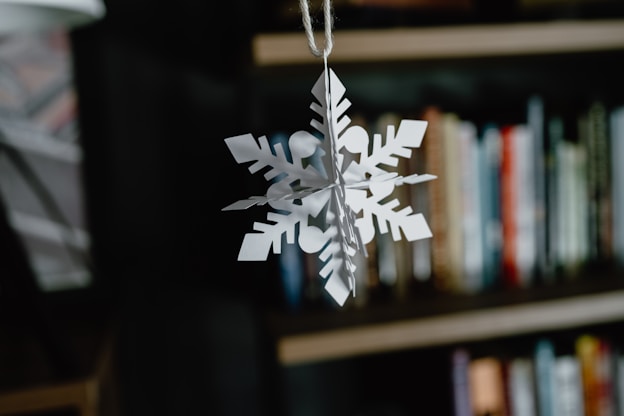A paper snowflake hanging from a book shelf