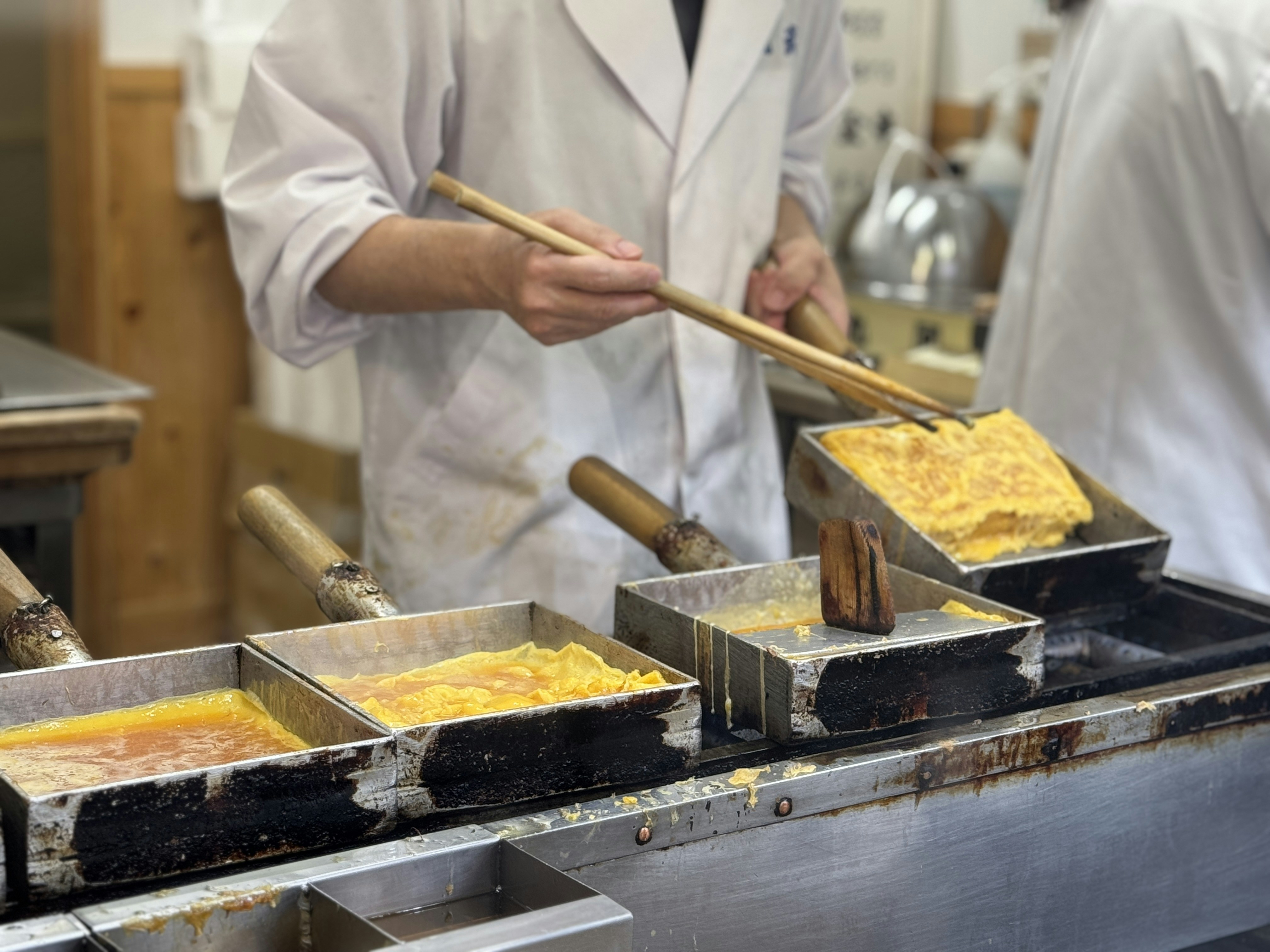 A person in a kitchen preparing food with chopsticks