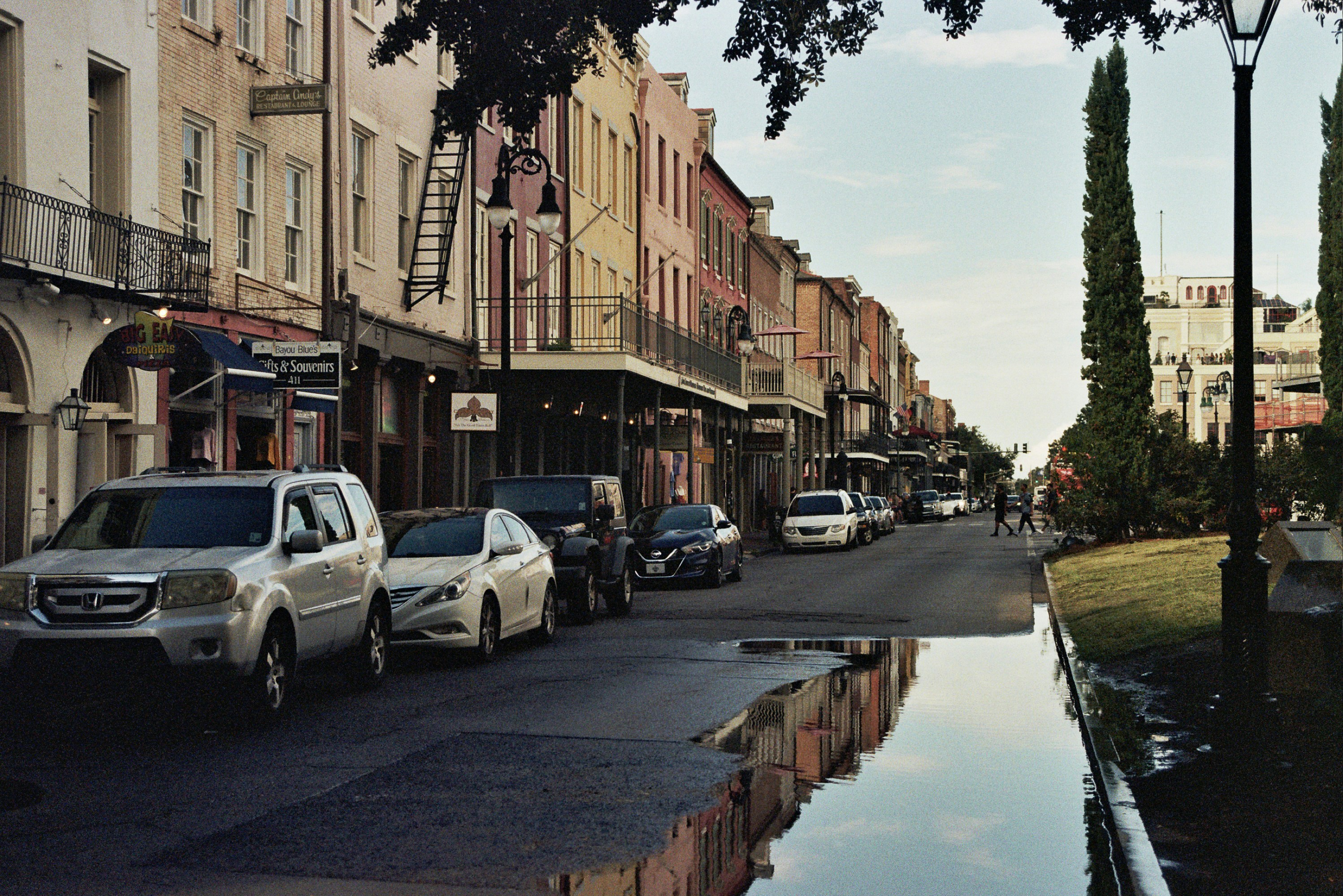 A street lined with parked cars next to tall buildings