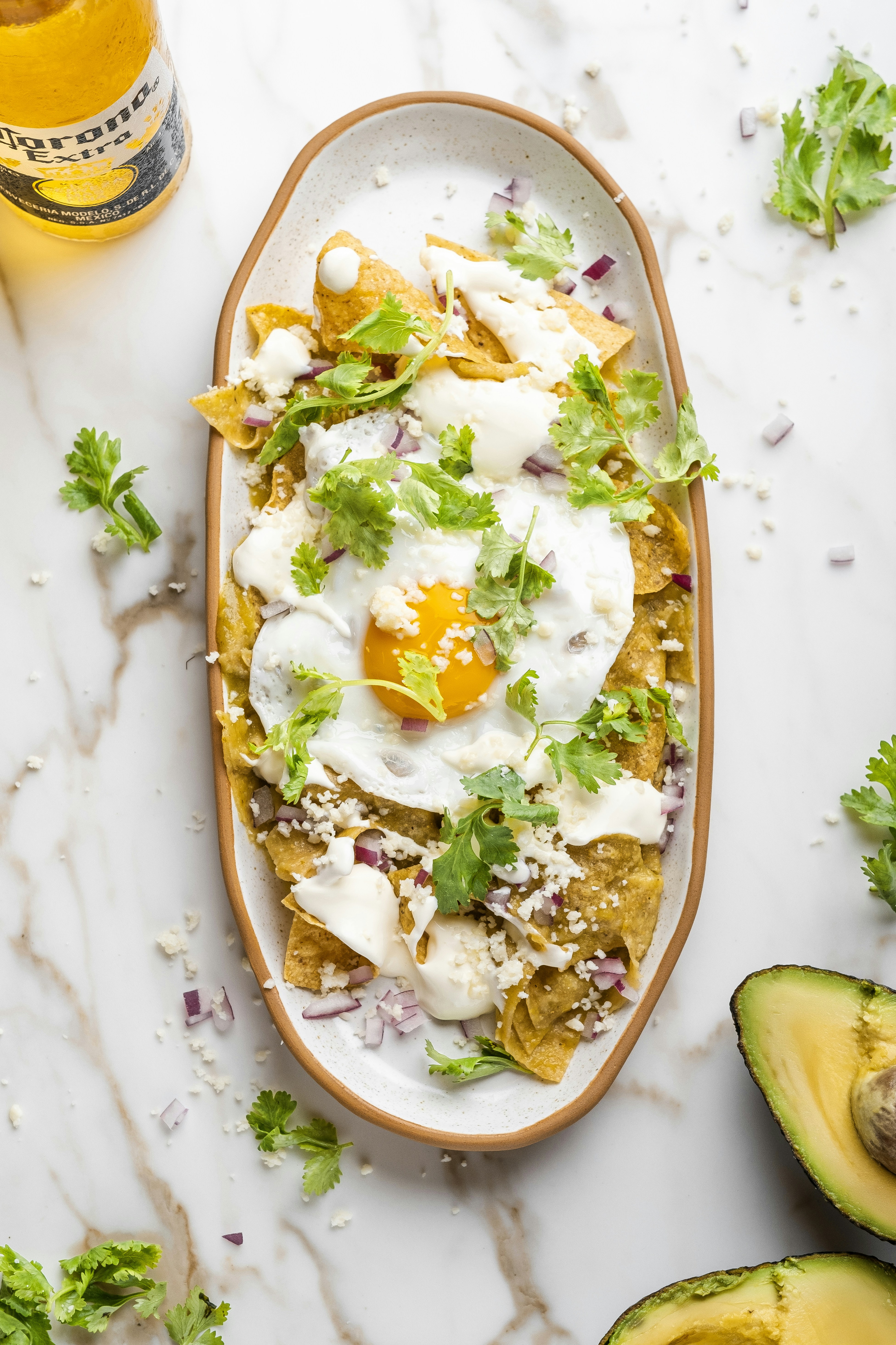 A plate of food with avocado and a bottle of beer