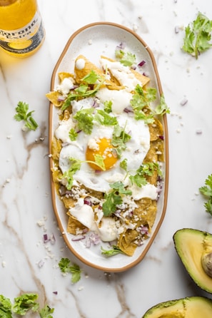 A plate of food with avocado and a bottle of beer
