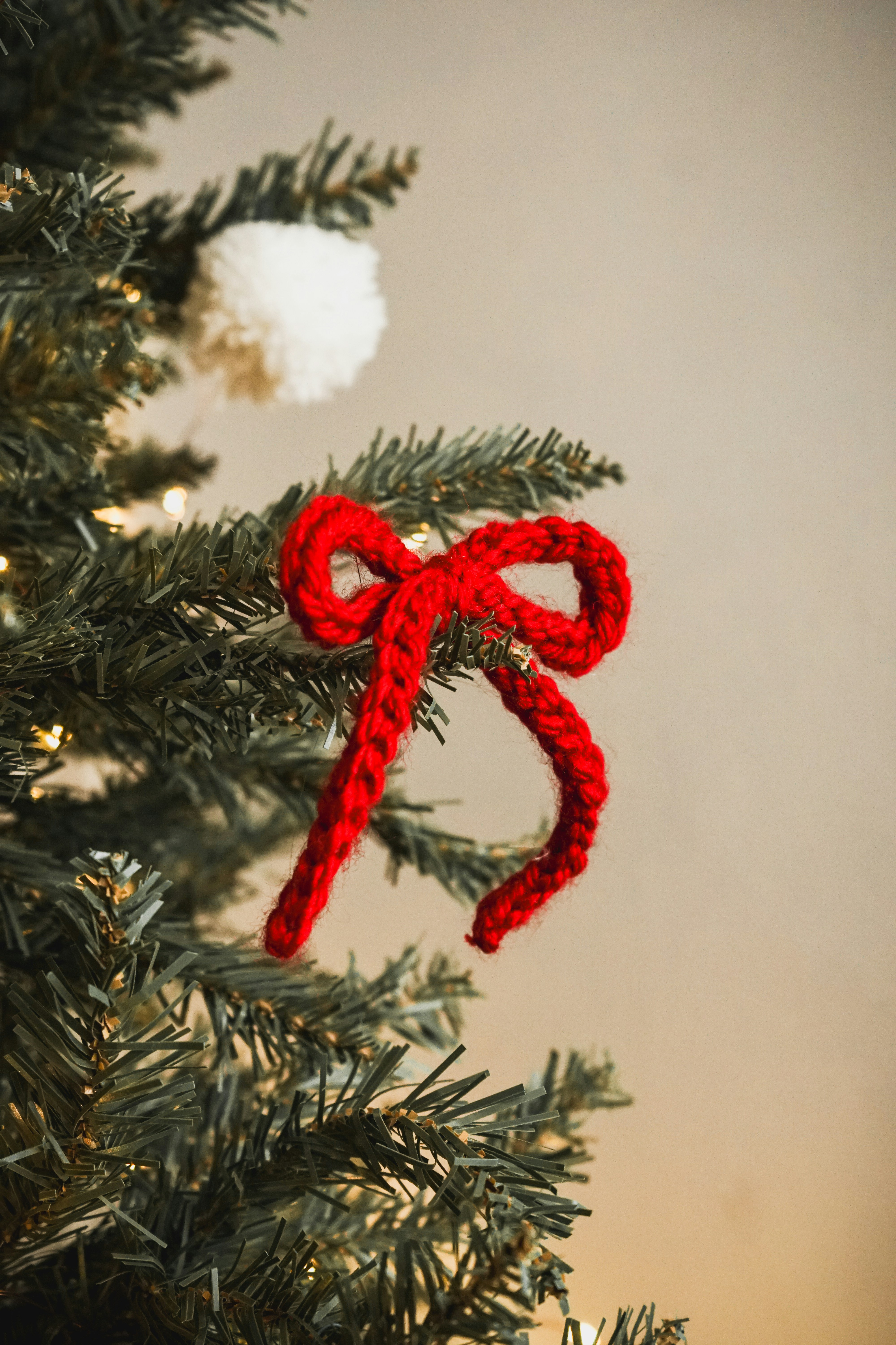 A crocheted bow ornament hanging from a christmas tree