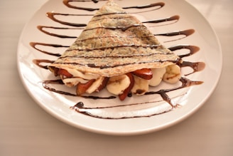 A white plate topped with a dessert covered in chocolate