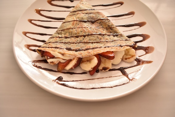A white plate topped with a dessert covered in chocolate
