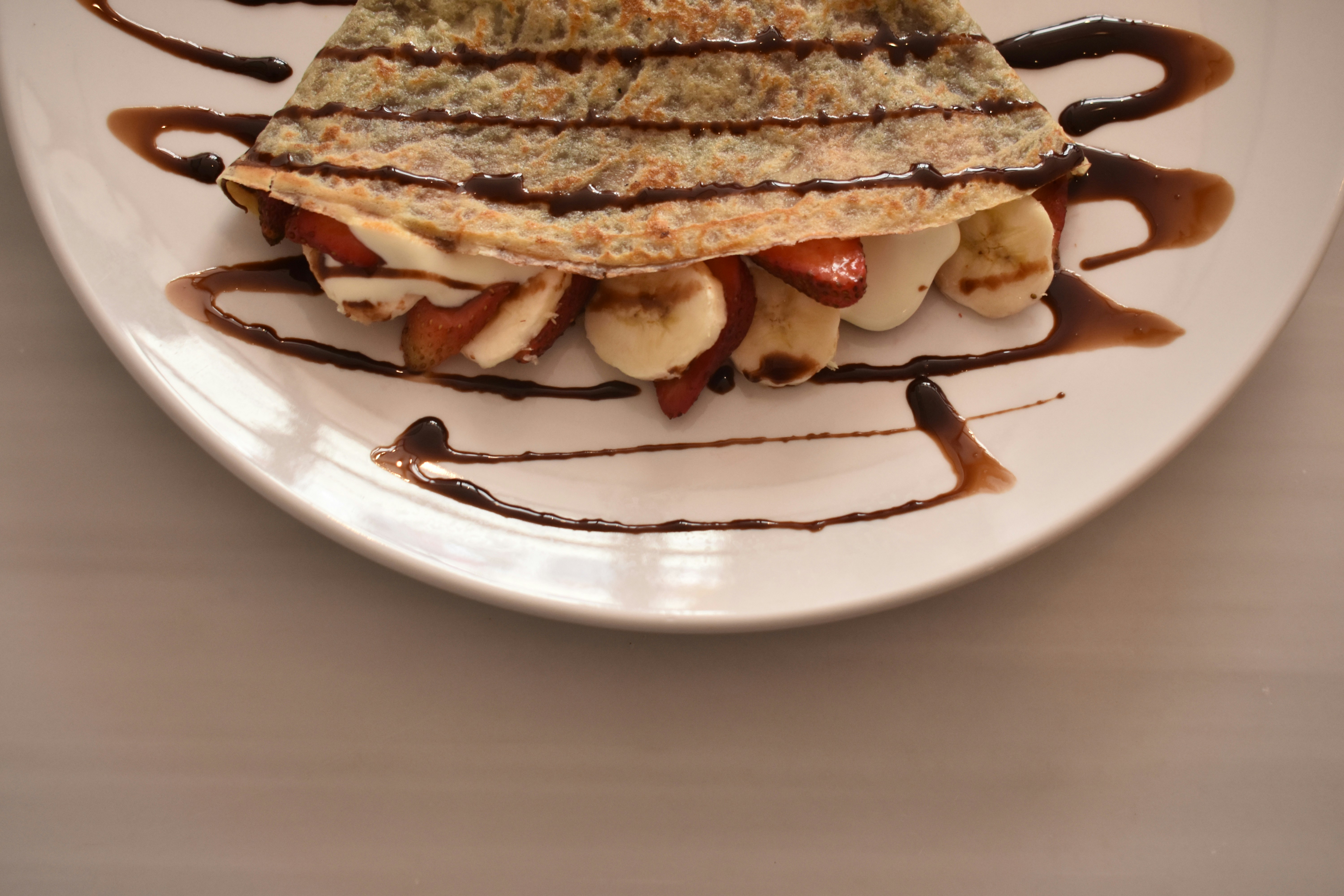 A white plate topped with a dessert covered in chocolate