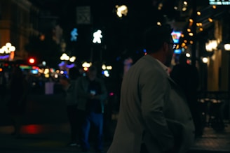 A man in a suit walking down a street at night