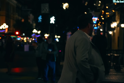 A man in a suit walking down a street at night