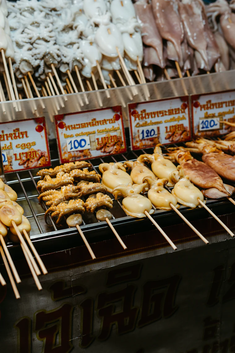Grilled seafood cooking over open coals at a Thai stall