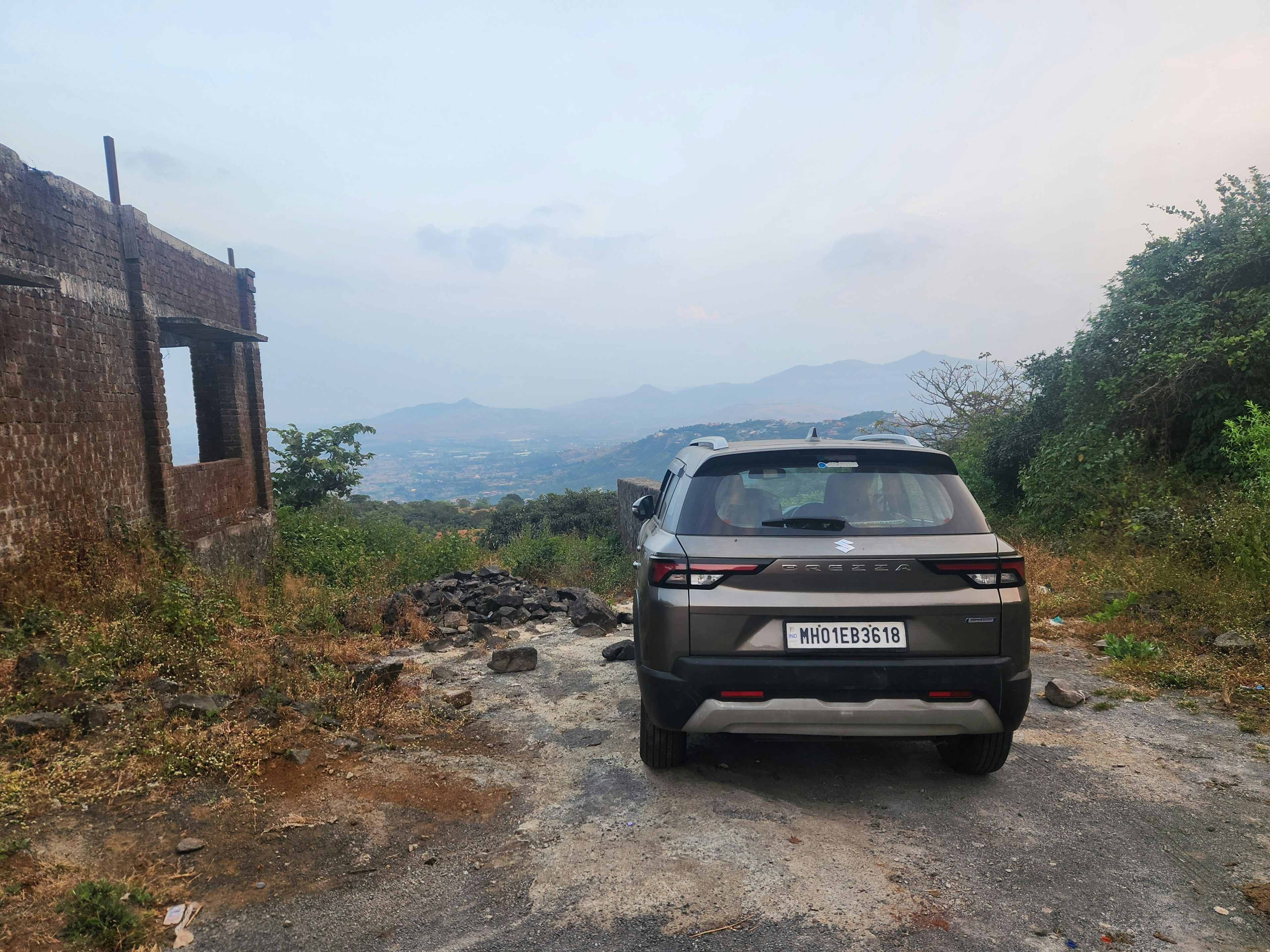 A car parked on a dirt road near a building