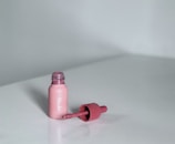 A pink bottle sitting on top of a white table