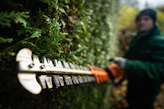 A person in a green jacket is holding a chainsaw