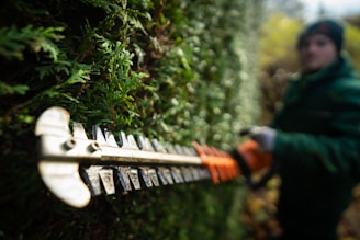 A person in a green jacket is holding a chainsaw