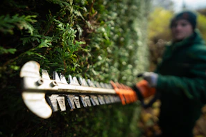 A person in a green jacket is holding a chainsaw