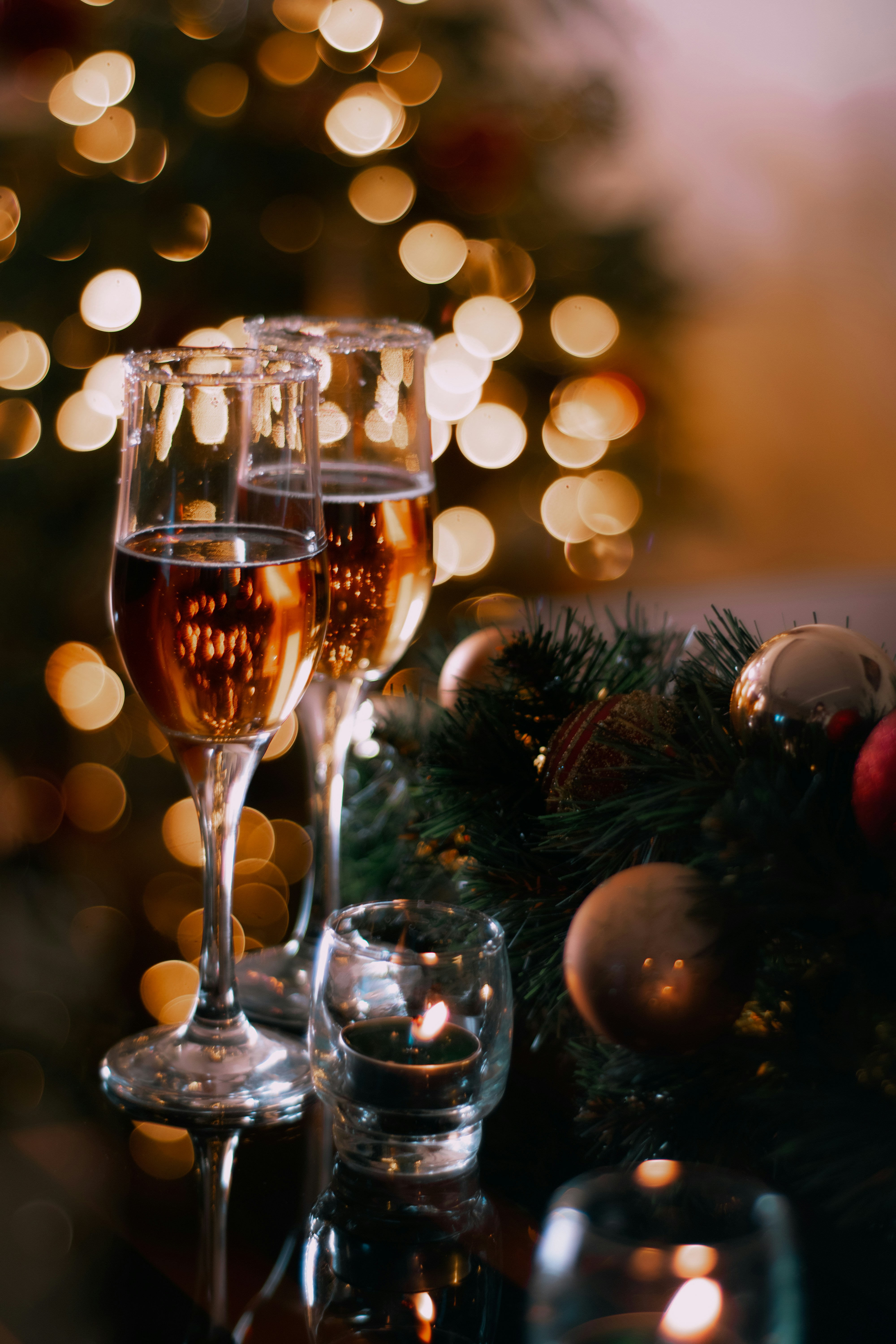 Two glasses of wine sitting on a table next to a christmas tree