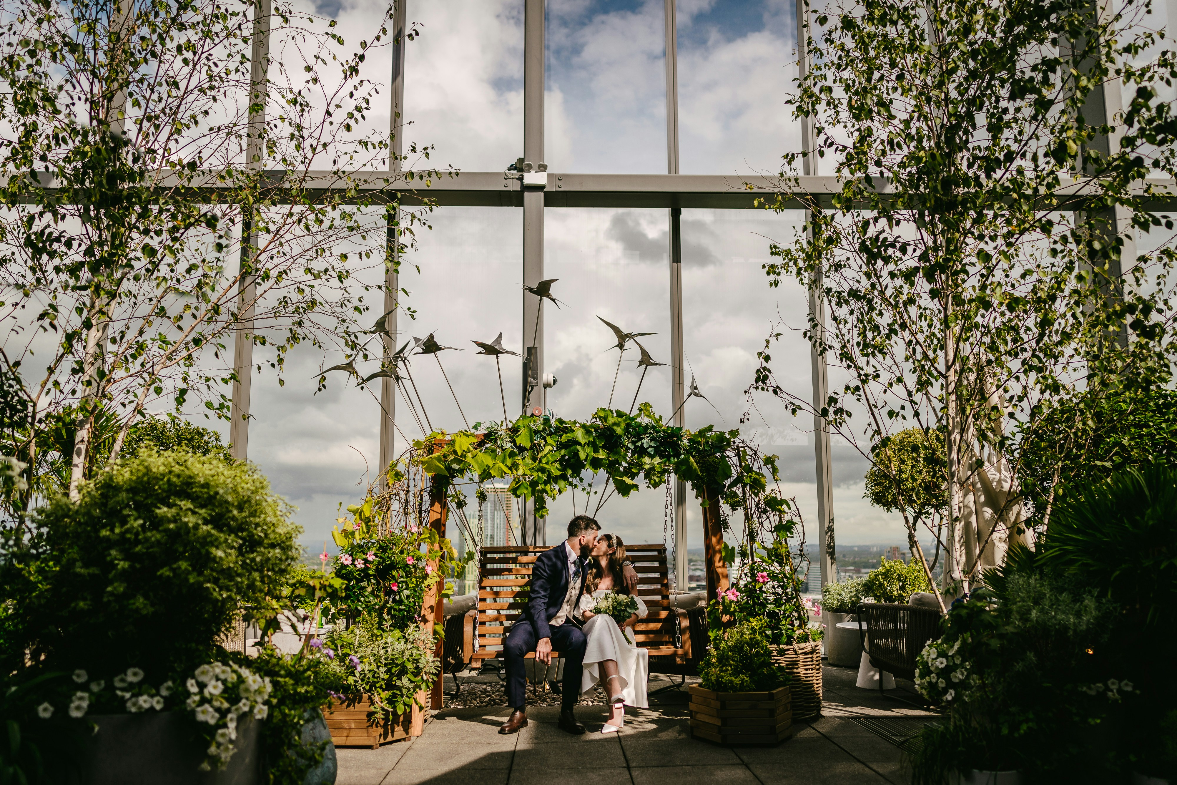 A bride and groom sitting on a bench in front of a window