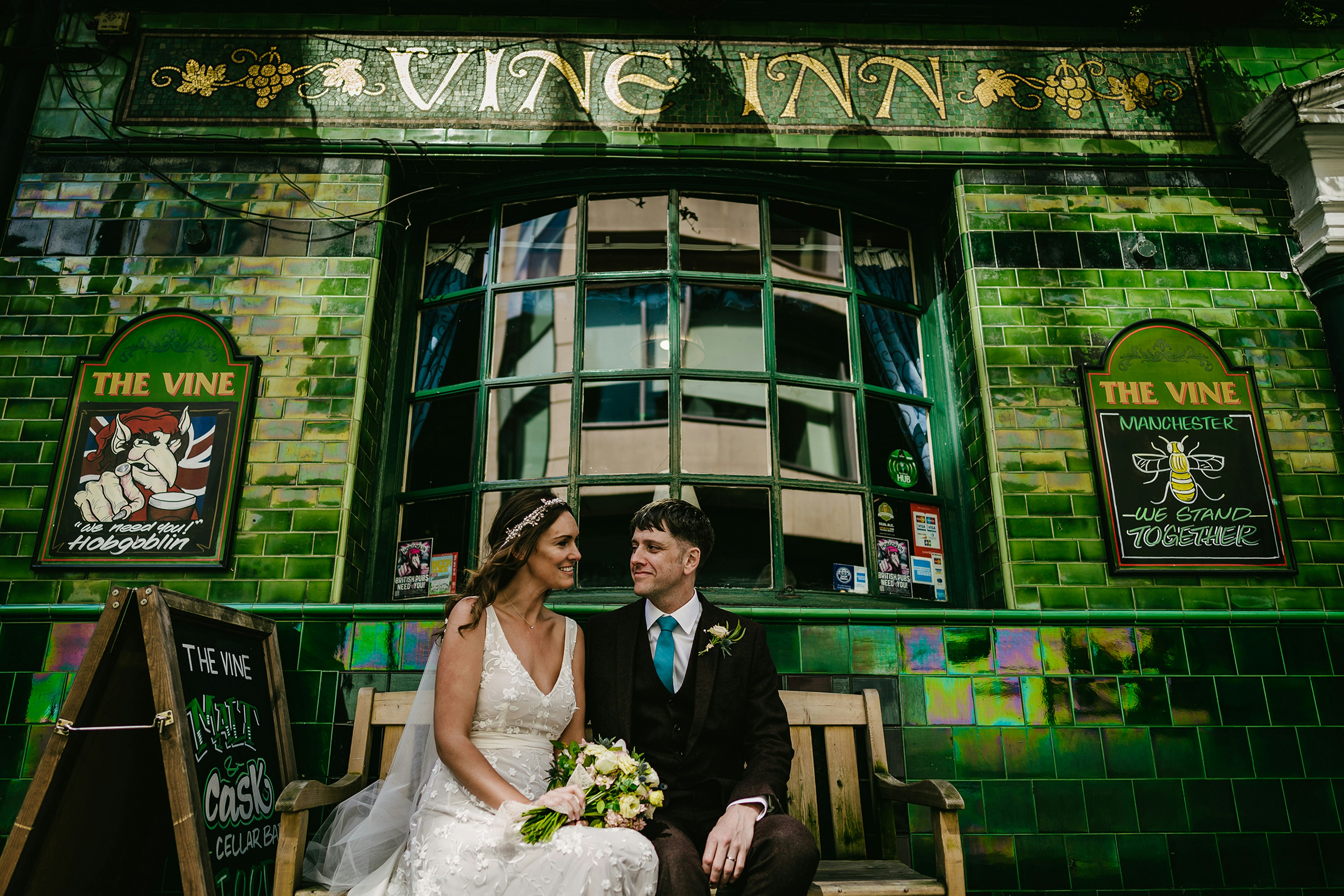 A bride and groom sitting on a bench in front of a building