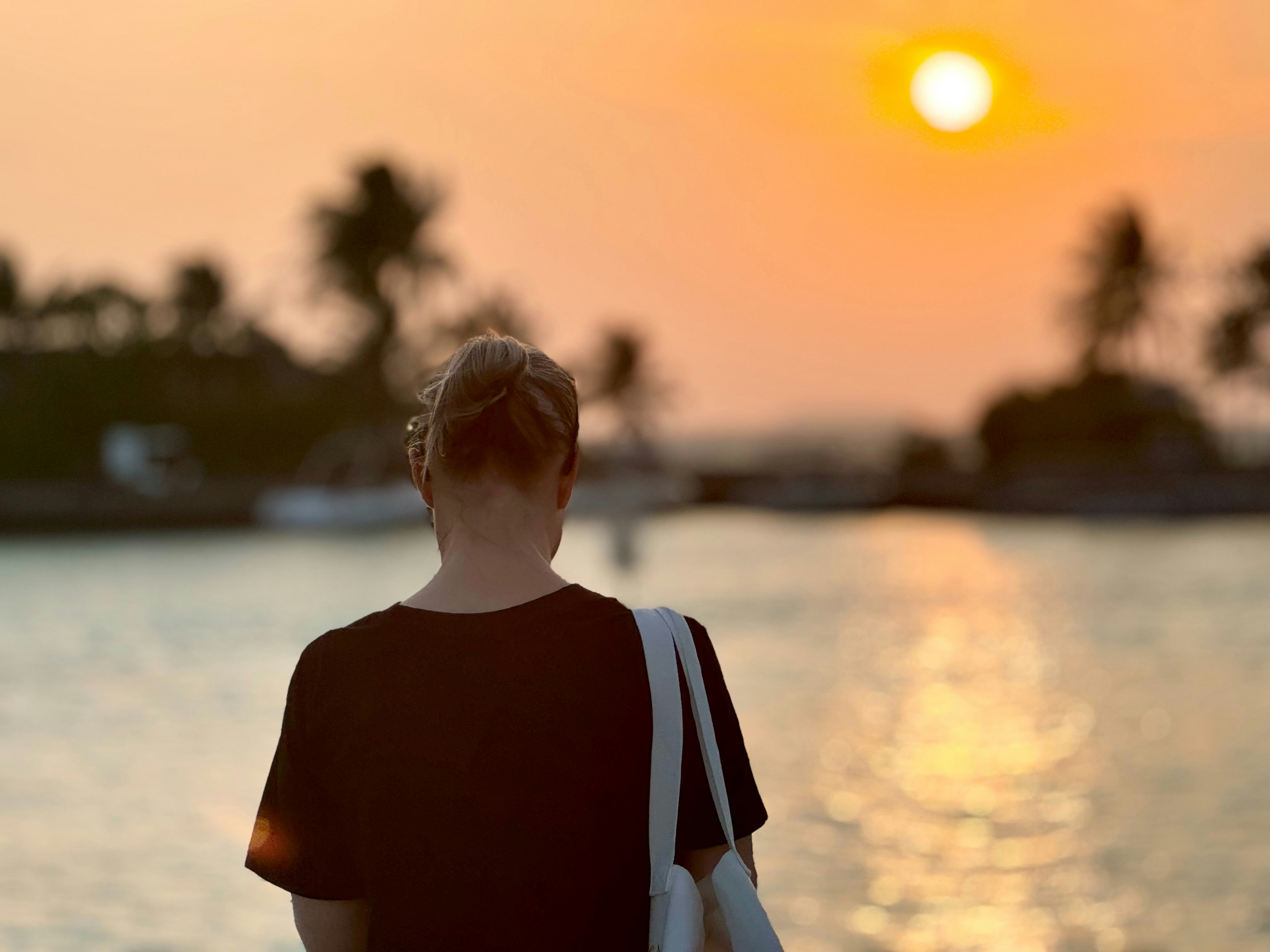 A woman standing on the beach watching the sun set