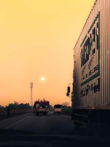 A truck driving down a highway next to a traffic light