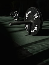 A row of black barbells in a dark gym