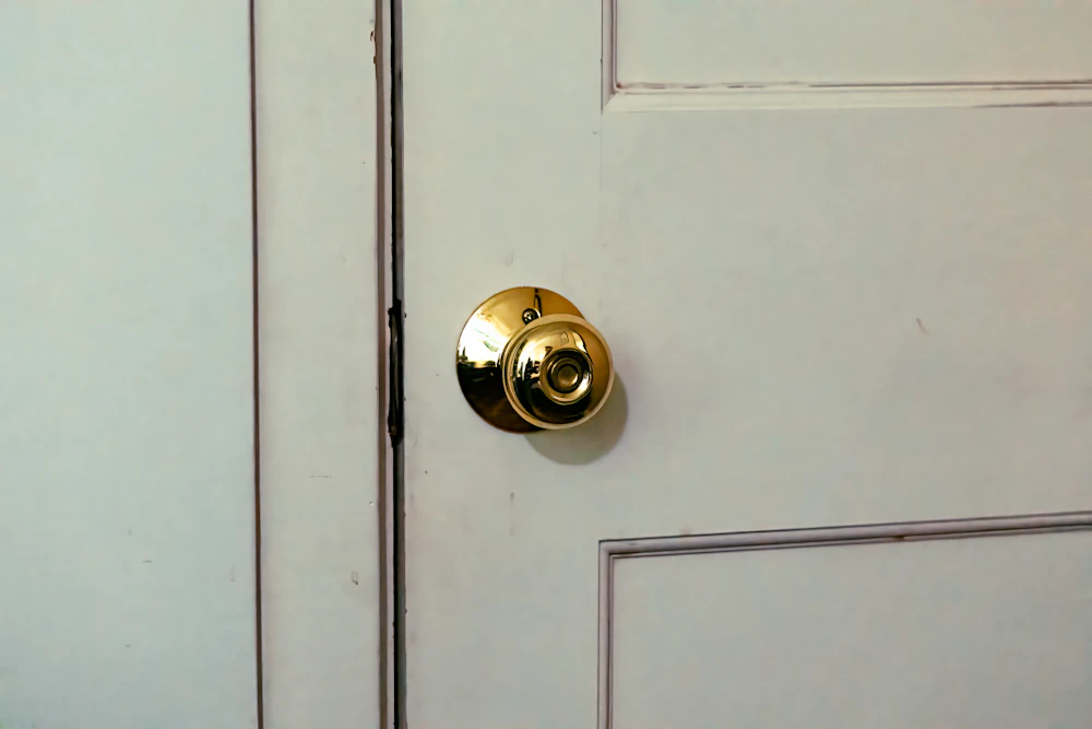 A brass doorknob with a keyhole on a pale grey panelled door