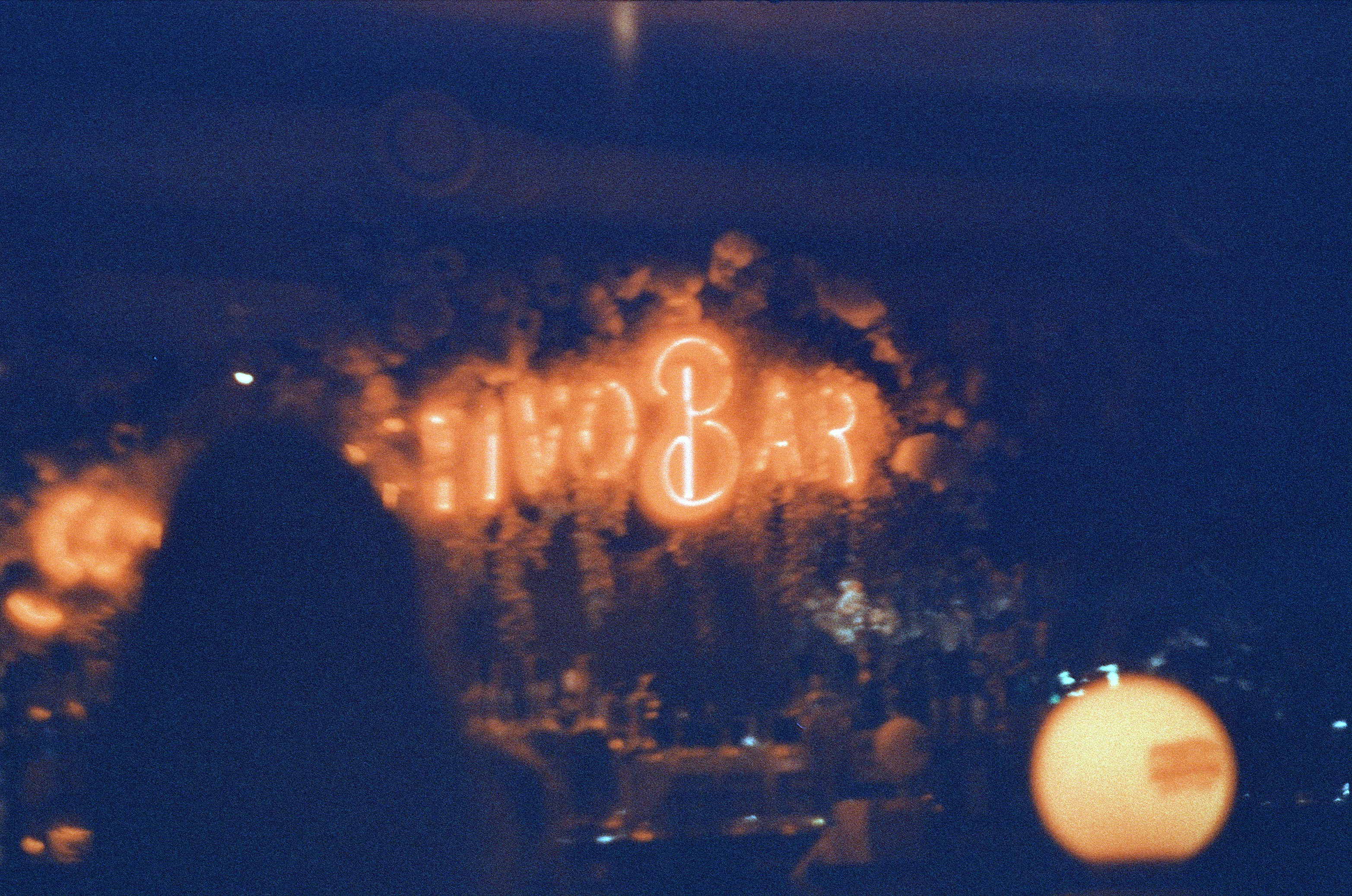 A blurry photo of a person standing in front of a neon sign