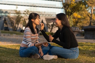 Two women sitting on the ground talking to each other