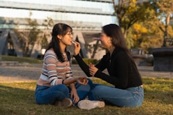 Two women sitting on the ground talking to each other
