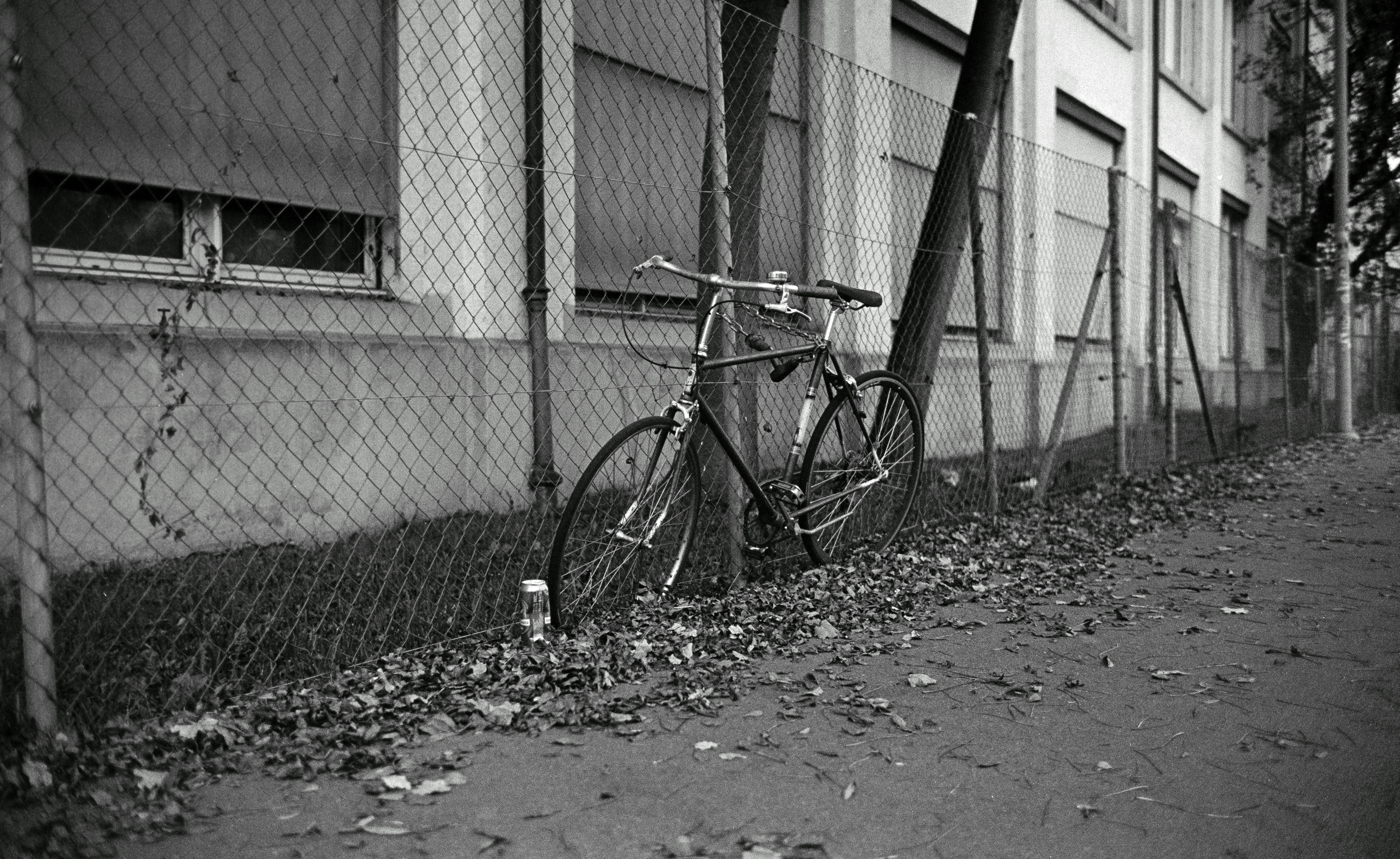 Ein Fahrrad, das an einem Zaun vor einem Gebäude lehnt