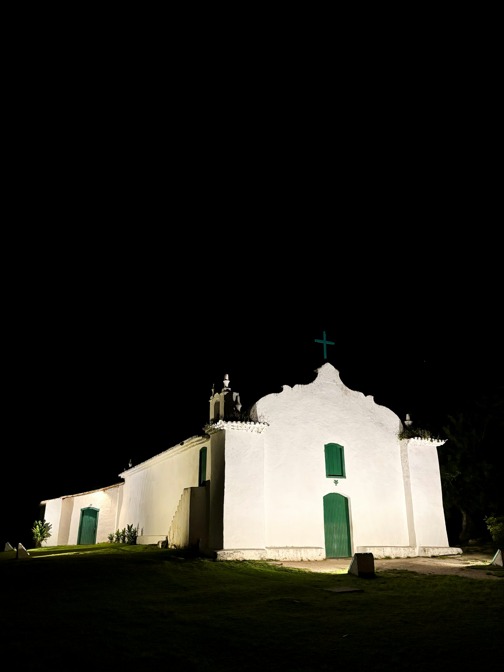 A church lit up at night with a cross on top