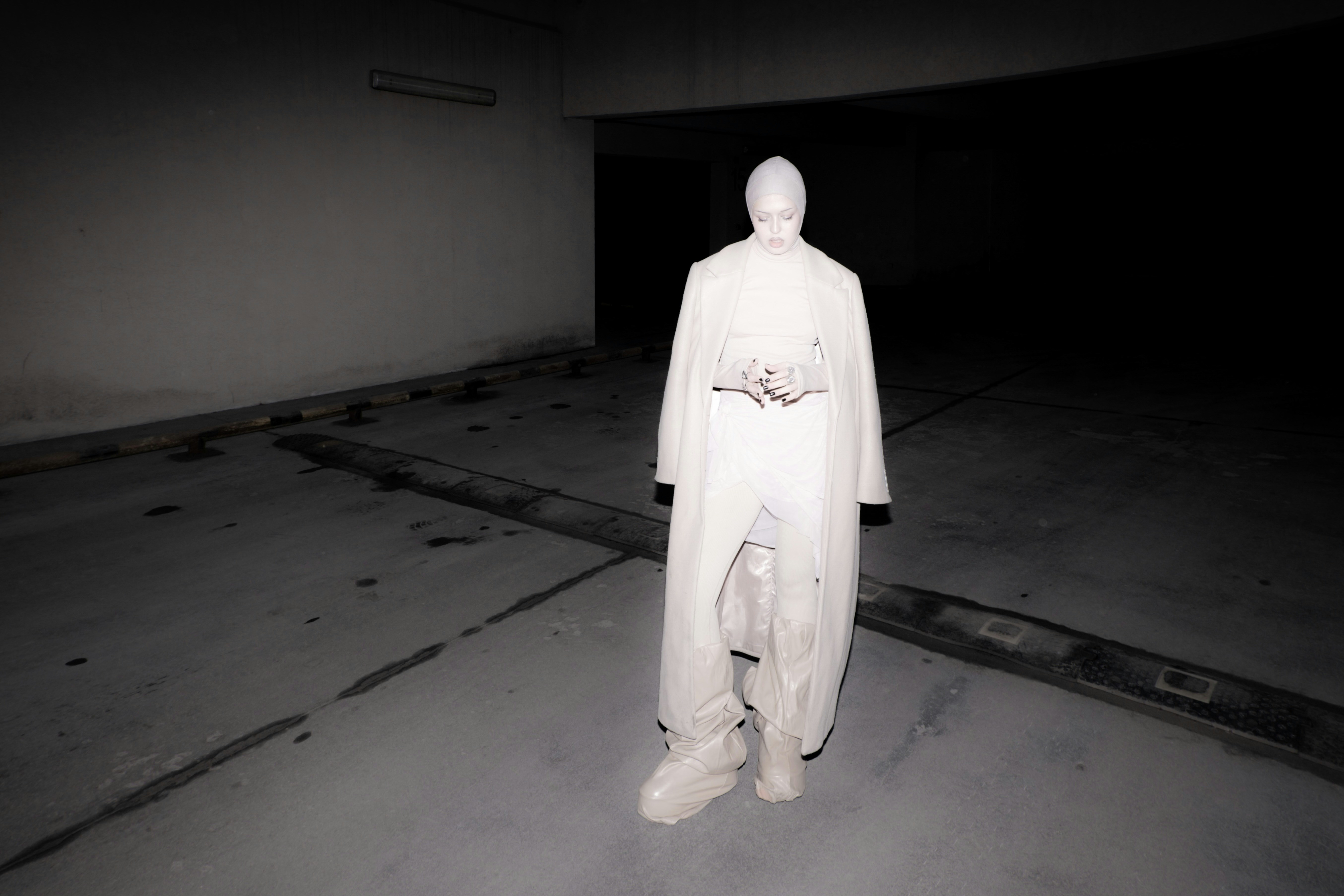 A man in a white suit standing in a dark room