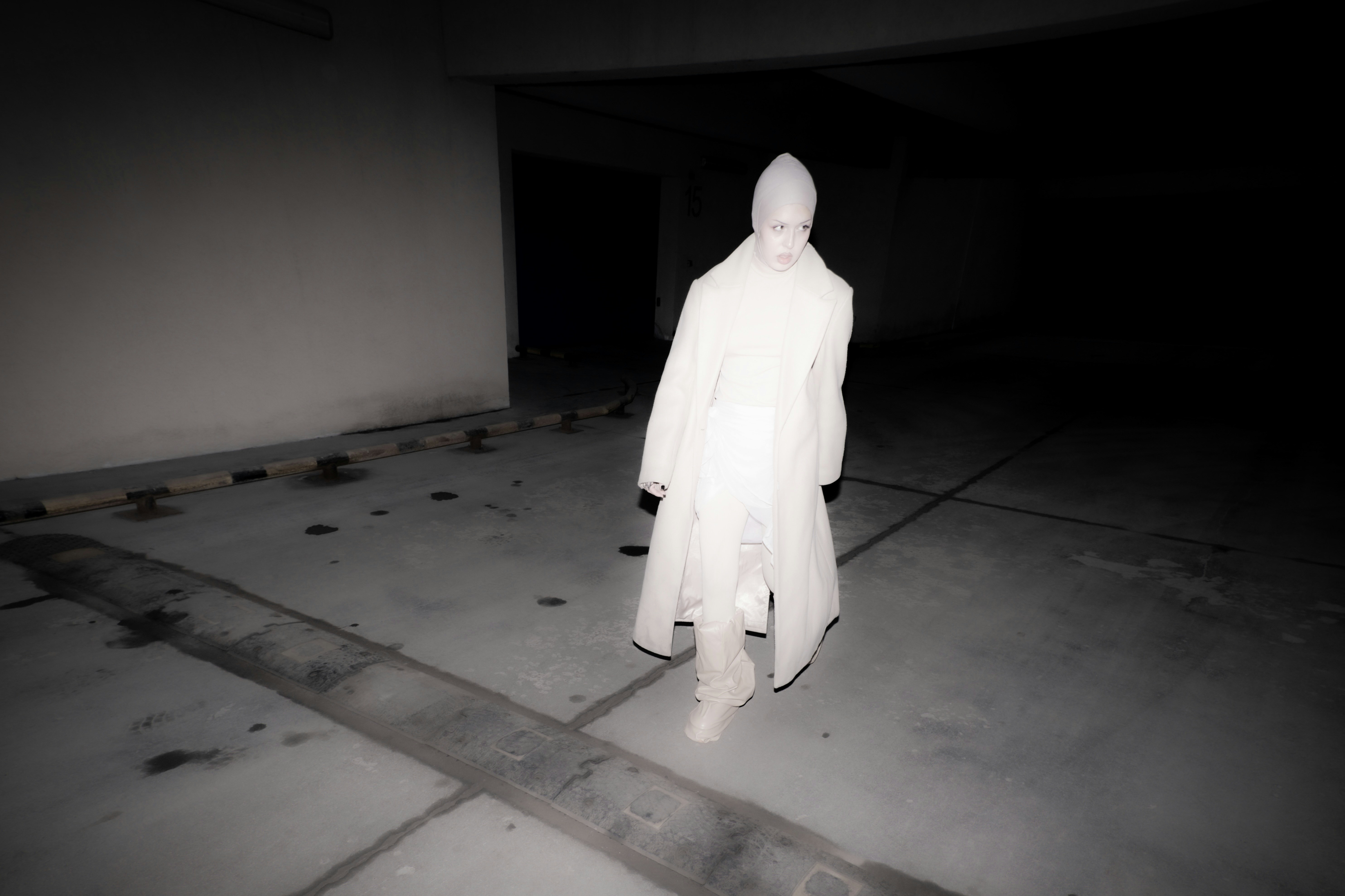 A person in a white robe standing in a dark room