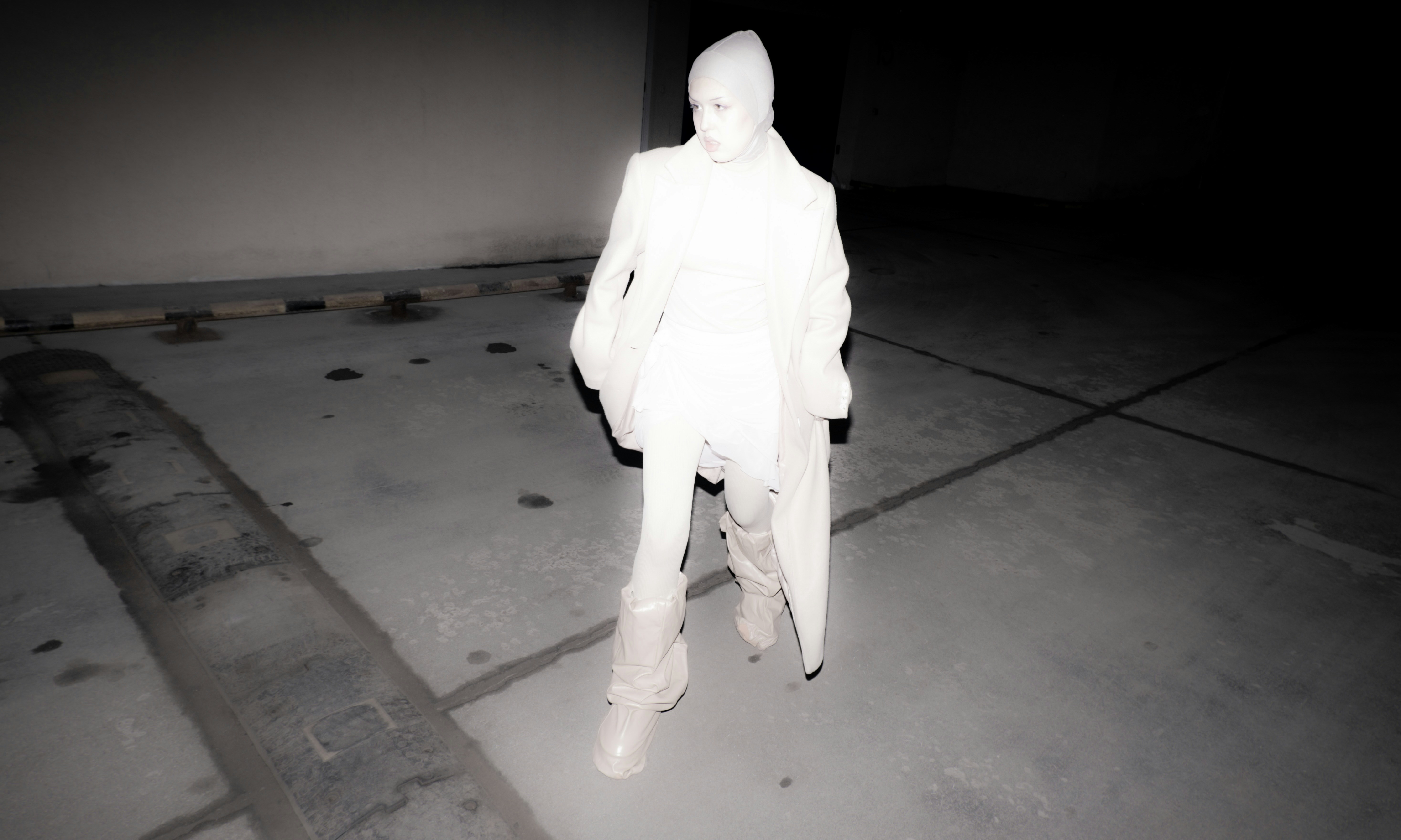 A man in a white suit standing on a sidewalk