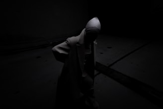 A person standing in the dark with a hood on