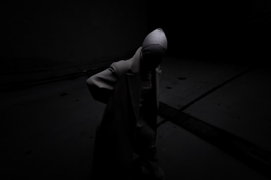 A person standing in the dark with a hood on