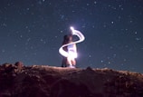 A man standing on top of a hill under a night sky