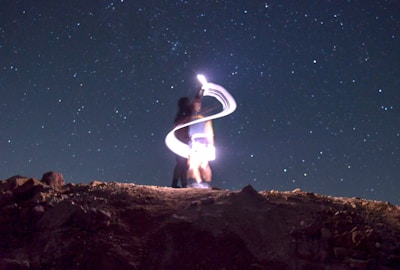 A man standing on top of a hill under a night sky