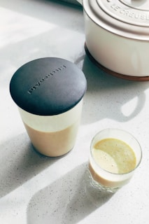A glass of liquid next to a pot on a table