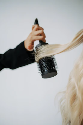 A woman blow drying her hair with a hair dryer