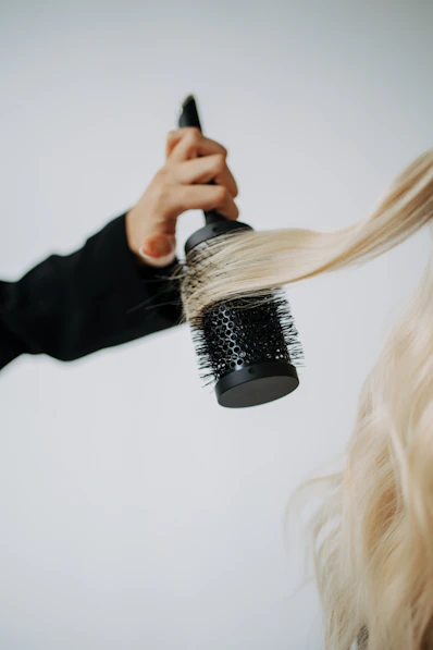 A woman blow drying her hair with a hair dryer