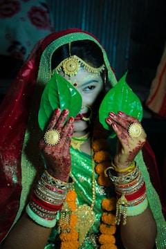 A woman dressed in a green and red outfit holding a green leaf