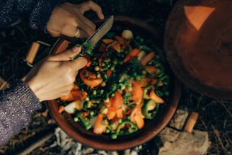 A person cutting up vegetables in a bowl