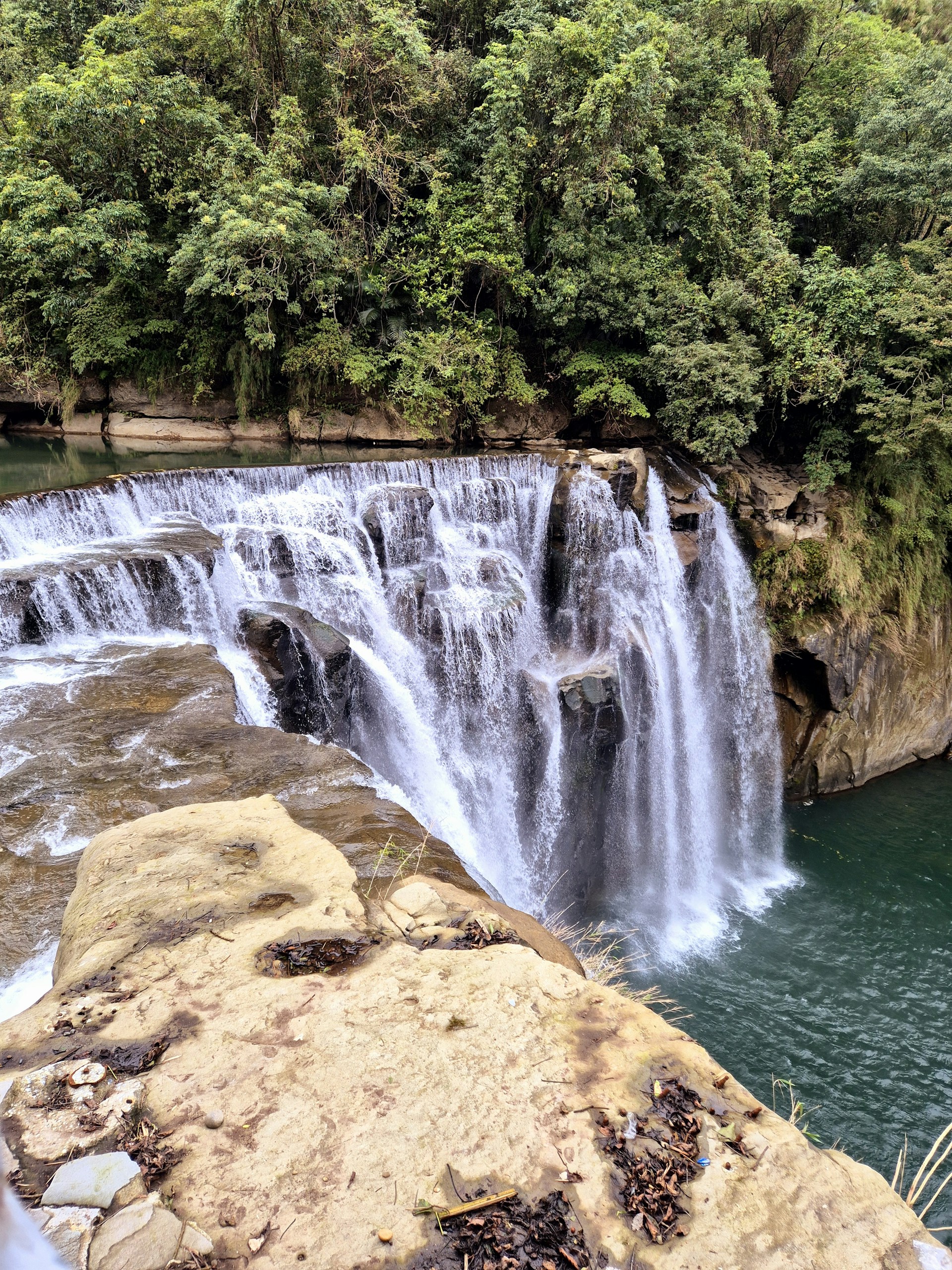 A waterfall with a man standing next to it