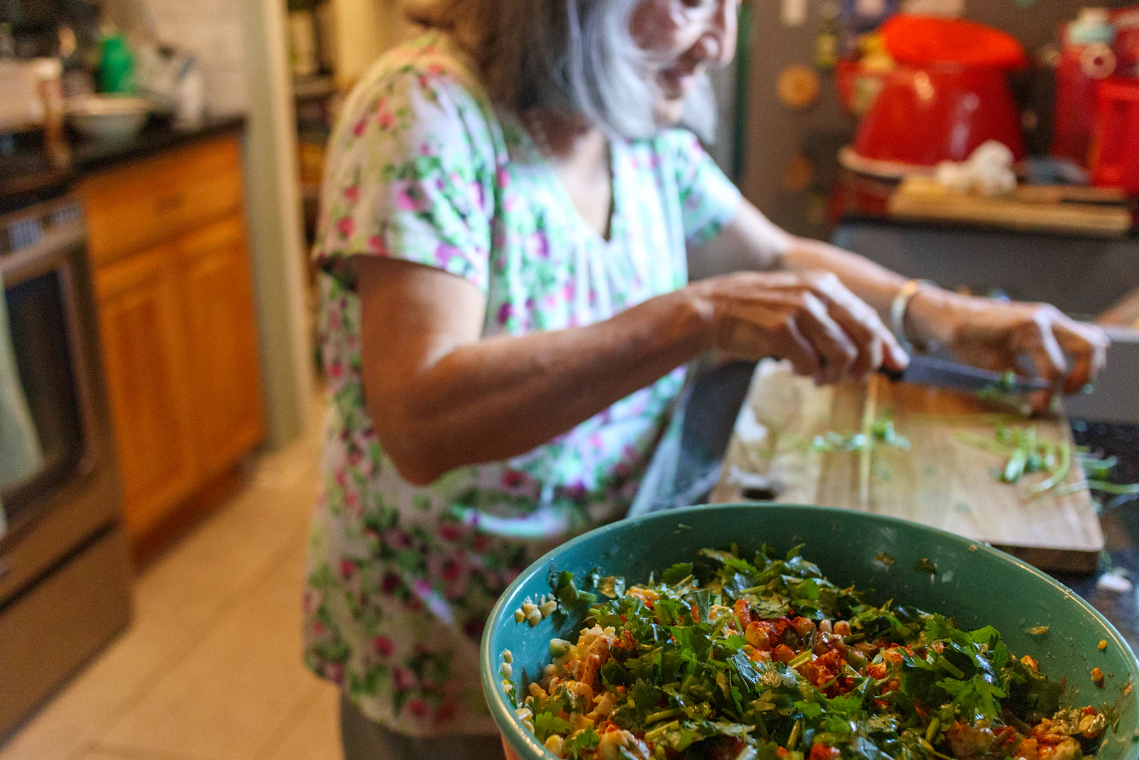 A woman preparing a fresh vegetable salad in her kitchen.
